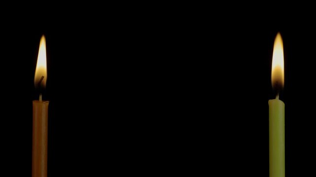 Church candles. Two lit candles on opposite sides of the screen.  4K video.