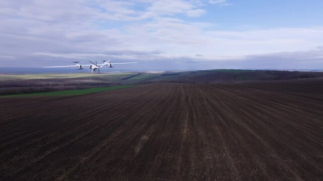 The white high-speed drone films and scans the surface of open fields. The drone makes aerial recordings of the surface of undeveloped land.Innovations and technologies in real estate and construction
