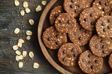 Naklejka premium Homemade Chocolate Chip Cookies on a Dark Wooden Table with Oats and Nuts