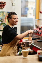 Young woman showcasing barista skills while crafting coffee at a trendy cafe this morning