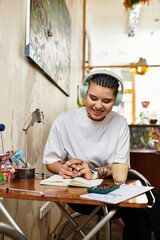 Fototapeta premium Young woman joyfully writing notes at a cozy cafe full of creativity and inspiration