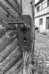 Rustic wooden door with vintage lock in a historic village captured on a cloudy day