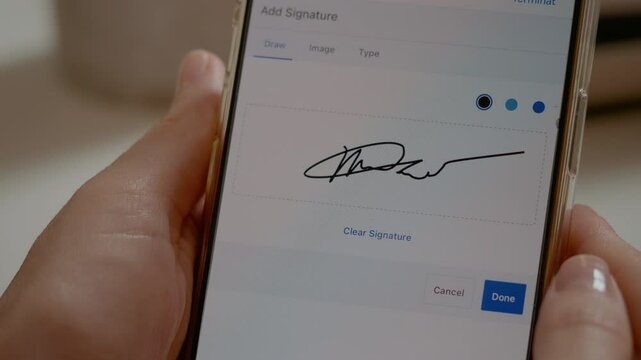 Woman is using her smartphone to create a digital signature. She carefully gestures with her finger on the screen while focused on the task.