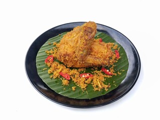 Ayam goreng serundeng or Fried chicken with fried grated coconut on plate isolated on white background 
