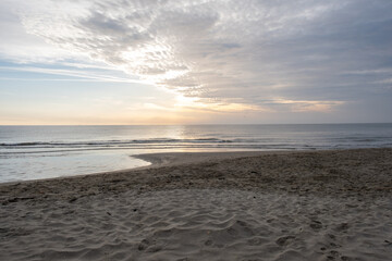 Serene sunrise over the sandy beach and sea waves