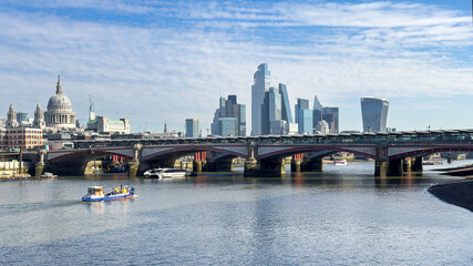 Blackfriars Bridge and the Rover Thames, with St Pauls Cathedral and the modern skyscrapers of the city of London in the distance.