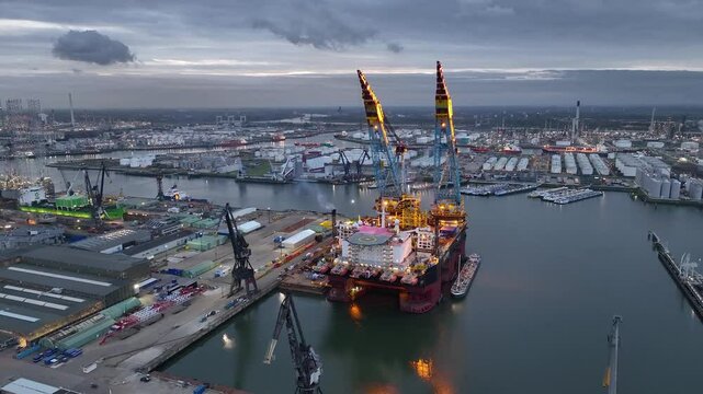 Rotterdam, Netherlands. Drone flight over industrial area with cargo ports, containers and a semi-submersible ship, heavy lifting crane. Machines designed for work at sea