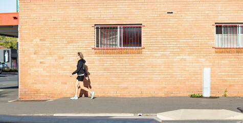 Person walking along footpath in front of brick building
