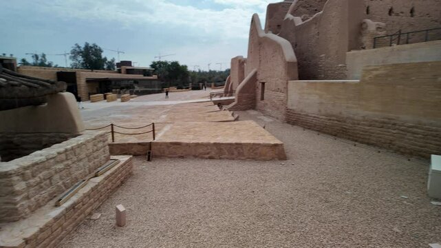 Diriyah, a UNESCO World Heritage site near Riyadh, featuring restored mud-brick buildings, a Saudi flag, and modern structures blending history and culture of Riyadh, Saudi Arabia