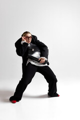 Curious young woman dressed formal outfit adjusted her stylish glasses, holding briefcase and looking to side against white studio background. Concept of business, challenges, development.