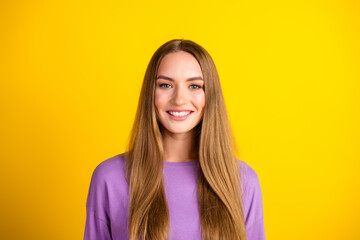 Portrait of a smiling young woman with long brown hair wearing a purple shirt against a vibrant...
