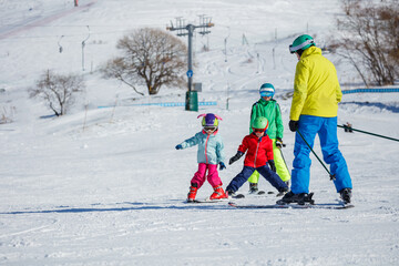 Skiers kids with adult enjoying fun day out on the snowy slopes