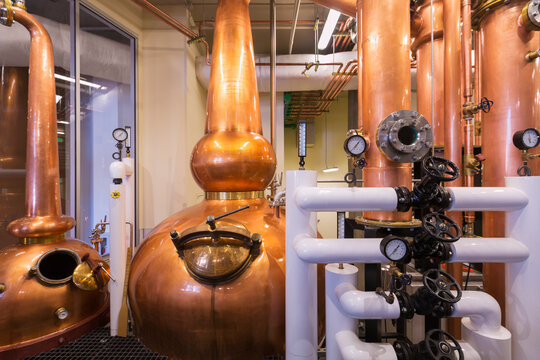 A copper still in a distillery, a large copper chamber and pipework for distilling. 