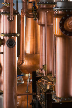 A copper still in a distillery, a large copper chamber and pipework for distilling. 