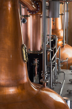 A copper still in a distillery, a large copper chamber and pipework for distilling. 