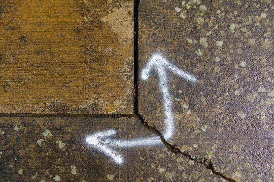 Spray painted arrows on broken pavement