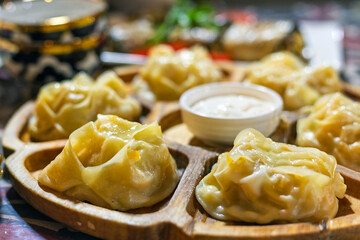 Still life with Manti food on wooden plate. Fresh traditional Uzbek Dumplings. Selective focus, blurred background
