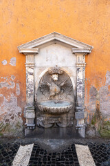 Ancient roman wall fountain in ruins showing a dragon spitting water