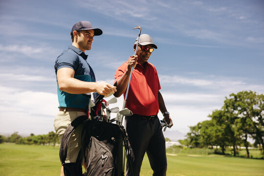 Golfers strategizing, choosing the right golf club from the bag for the perfect shot.