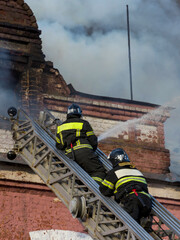 Two firefighters are on a ladder