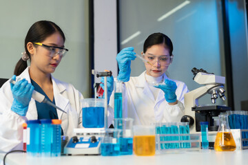 Fototapeta premium Scientist analyzing and dropping a sample into a glassware.