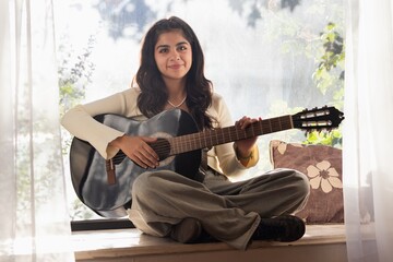 woman practices guitar and smiles 