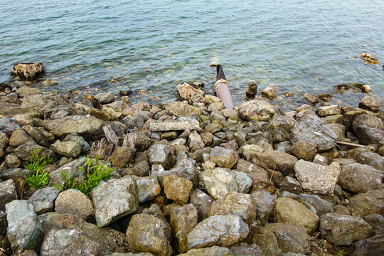 Storm sewer outlet, a pipe hidden under rocks discharging effluents and sewage into the Strait of Juan de Fuca in Port Angeles.