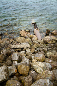 Storm sewer outlet, a pipe hidden under rocks discharging effluents and sewage into the sea