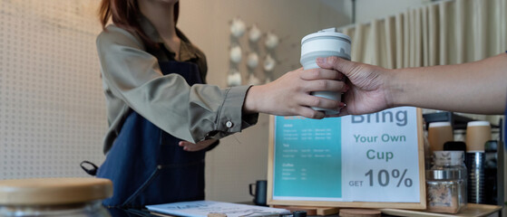 Customer Engagement and Discounts. A barista handing over a reusable cup with a discount offer.