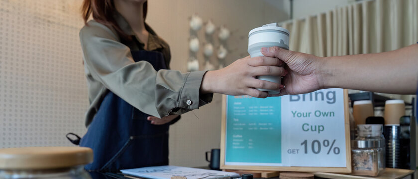 Customer Engagement and Discounts. A barista handing over a reusable cup with a discount offer.