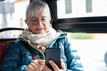 Portrait of a smiling senior woman sitting on the passenger seat during a sightseeing tour on a bus...