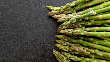 Top view of a fresh organic green asparagus on a black granite stone table. Copy space.
