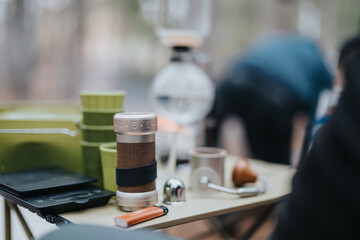 Close-up of a coffee preparation setup during a winter outdoor picnic featuring handcrafted items, creating a cozy and inviting scene perfect for enjoying nature.