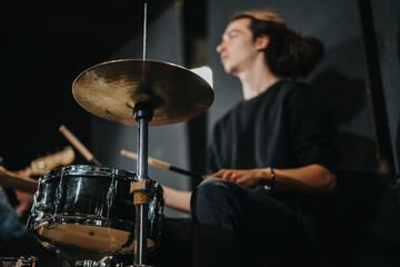 Obraz premium A drummer is engaged in playing drums during a band practice session, creating an energetic atmosphere. The image captures the focus and passion of musical performance.