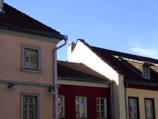 Colorful old European buildings with red-tiled roofs and pastel facades under a clear blue sky