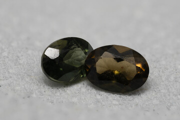 Close-up of Natural Kornerupine Gemstones in Olive-Green and Deep Brown Colors on Textured Surface