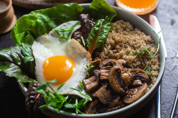 Quinoa with egg, mushrooms and salad in a plate on the table. Bowl