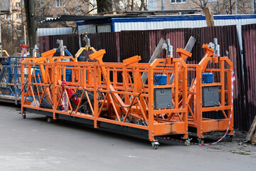 Multiple suspended scaffold platforms stand on site, showcasing industrial construction equipment used for facade work and repairs.