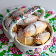 Freshly baked homemade cookies dusted with powdered sugar, served in a vintage ceramic bowl with a floral pattern.