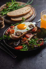 Scrambled eggs with bacon, tomato and lettuce in a plate. Bowl