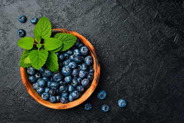 Close-up of blueberries in a bowl on a black slate table.