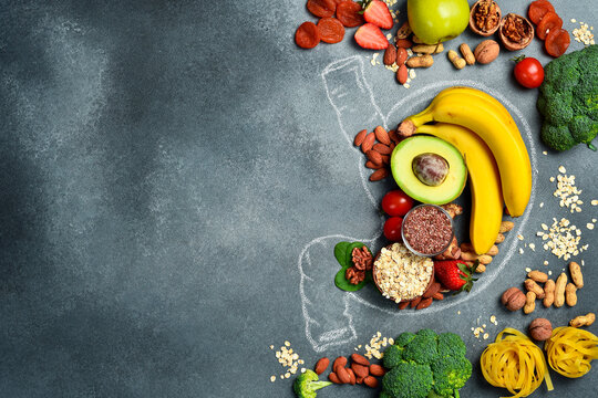 A set of fresh fruits, vegetables and nuts laid out in the shape of a stomach. A chalk drawing of a human stomach. The best foods for healthy digestion.