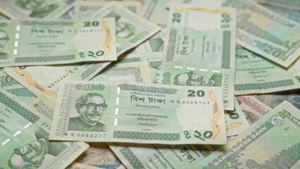 Bangladesh banknotes featuring various denominations and designs scattered, highlighting the country's currency, taka, and financial symbolisms.