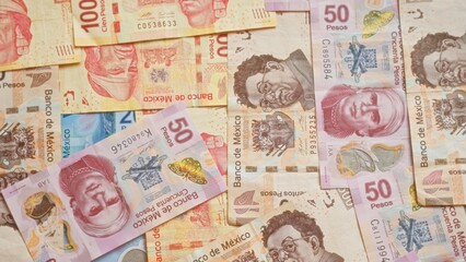 Mexican banknotes in various denominations spread out, showcasing colorful pesos currency in mexico, highlighting financial themes of money, banking, economy, and cash transactions.