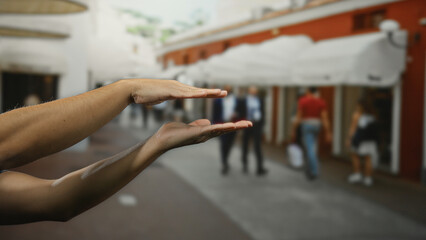 Hands of a man creating a frame gesture on a bustling urban city street with blurred pedestrians, capturing the dynamic outdoor atmosphere.