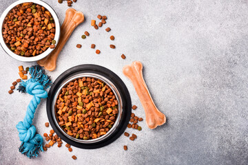 Pet bowl with dry food on a gray textured background. Studio photo.