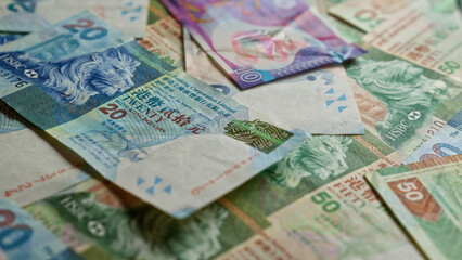 Hong kong dollar banknotes scattered on a flat surface, displaying various denominations and intricate designs.
