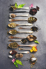 Different types of tea in vintage spoons. Flat lay. On a gray stone table.