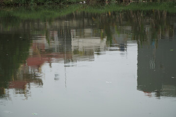 Tranquil Reflection of Urban Buildings and Greenery on Still Water in a Serene Environment