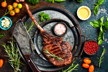 Steak on the bone. Grilled Tomahawk steak with rosemary and spices on a metal plate. Top view.